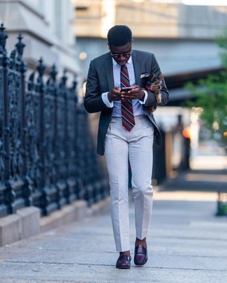 Comment porter un blazer gris foncé: Pense à marier un blazer gris foncé avec un pantalon de costume blanc pour dégager classe et sophistication. Complète ce look avec une paire de slippers en cuir bordeaux.