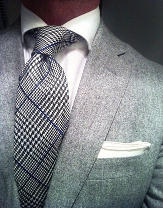 Comment porter une cravate blanc et bleu marine à 30 ans: L'association d'un blazer gris et d'une cravate blanc et bleu marine peut te démarquer de la foule.