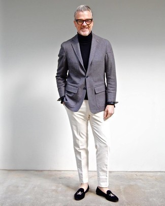 Comment porter des chaussures brodées quand il fait chaud après 50 ans: Associe un blazer en laine gris avec un pantalon de costume blanc pour une silhouette classique et raffinée. Cet ensemble est parfait avec une paire de slippers en velours brodés noirs.
