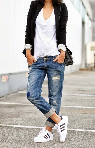 Comment porter un blazer noir pour un style relax: Opte pour un blazer noir avec un jean boyfriend déchiré bleu pour une impression décontractée. Si tu veux éviter un look trop formel, termine ce look avec une paire de chaussures de sport blanches.