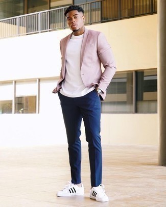 Comment porter un blazer rose: Associe un blazer rose avec un pantalon chino bleu marine pour prendre un verre après le travail. Jouez la carte décontractée pour les chaussures et choisis une paire de baskets basses en cuir blanches et noires.