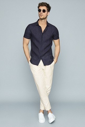Tenue: Chemise à manches courtes en lin bleu marine, Pantalon chino blanc, Baskets basses en toile blanches, Lunettes de soleil noires