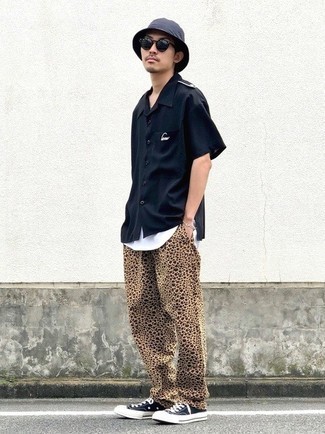 Comment porter un pantalon chino imprimé léopard beige: Harmonise une chemise à manches courtes noire avec un pantalon chino imprimé léopard beige pour une tenue idéale le week-end. Termine ce look avec une paire de baskets basses en toile noires et blanches.