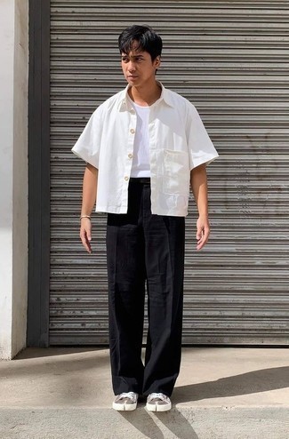Comment porter un pantalon chino noir: Essaie d'associer une chemise à manches courtes blanche avec un pantalon chino noir pour obtenir un look relax mais stylé. Complète ce look avec une paire de baskets basses en toile marron.