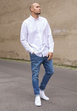 Comment porter un jean bleu avec des baskets basses en toile blanches en été: Associe une chemise à manches longues blanche avec un jean bleu pour un look de tous les jours facile à porter. Une paire de baskets basses en toile blanches est une option judicieux pour complèter cette tenue. On craque complètement pour cette tenue, tellement estivale.