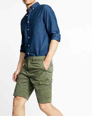 Comment porter une chemise à manches longues en chambray bleue en été: Associe une chemise à manches longues en chambray bleue avec un short olive pour un déjeuner le dimanche entre amis. Bref, cette tenue d'été est canon.