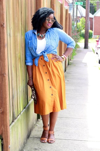 Comment porter une jupe orange: Pense à porter une chemise en jean bleu clair et une jupe orange pour une tenue confortable aussi composée avec goût. Termine ce look avec une paire de sandales à talons en cuir marron clair.