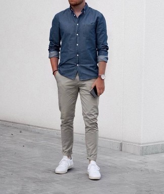 Comment porter un pantalon chino gris en été: Essaie de marier une chemise en jean bleu marine avec un pantalon chino gris pour obtenir un look relax mais stylé. Cet ensemble est parfait avec une paire de baskets basses en toile blanches. Nous aimons absolument cette tenue qui est parfaite pour l'été.