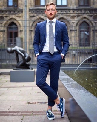 Comment porter une cravate gris foncé pour un style elégantes à 20 ans: Pense à opter pour un costume bleu et une cravate gris foncé pour dégager classe et sophistication. Mélange les styles en portant une paire de baskets basses en toile bleu marine et blanc.