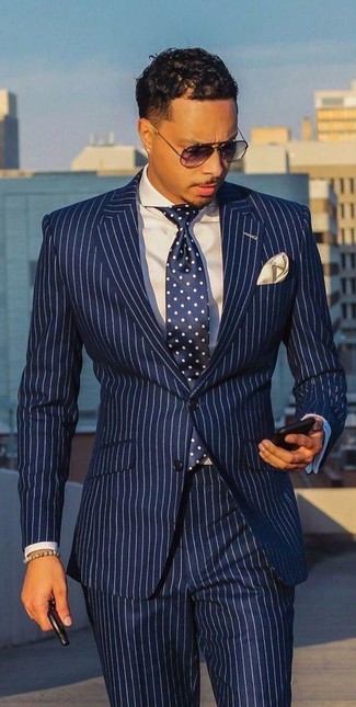 Comment porter une cravate bleu marine à 20 ans: Associe un costume à rayures verticales blanc et bleu marine avec une cravate bleu marine pour dégager classe et sophistication.
