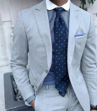 Comment porter une cravate á pois bleu marine et blanc: Harmonise un costume gris avec une cravate á pois bleu marine et blanc pour un look classique et élégant.