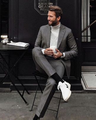 Comment porter un pull à col roulé blanc avec un costume gris à 30 ans: Opte pour un costume gris avec un pull à col roulé blanc pour une silhouette classique et raffinée. Décoince cette tenue avec une paire de baskets basses en toile blanches et noires.