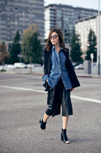 Comment porter une chemise en jean bleue: Porte une chemise en jean bleue et une jupe-culotte en cuir noire pour obtenir un look relax mais stylé. Cette tenue est parfait avec une paire de bottines en cuir découpées noires.