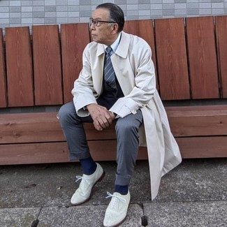 Comment porter un imperméable pour un style elégantes après 60 ans: Harmonise un imperméable avec un costume gris foncé pour un look classique et élégant. Cette tenue est parfait avec une paire de chaussures brogues en cuir blanches.
