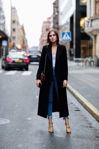 Comment porter un jean bleu: Pour créer une tenue idéale pour un déjeuner entre amis le week-end, pense à harmoniser un manteau noir avec un jean bleu. Assortis ce look avec une paire de sandales à talons en cuir dorées.