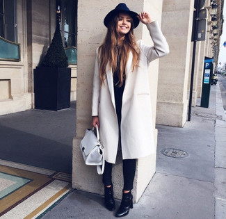 Comment porter un cartable en cuir blanc: Harmonise un manteau blanc avec un cartable en cuir blanc pour un look confortable et décontracté. Cette tenue est parfait avec une paire de bottines en cuir noires.