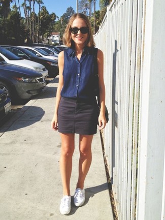 Comment porter une chemise boutonnée sans manches en denim bleu marine avec des baskets basses blanches