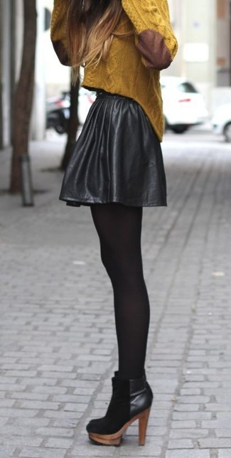 Comment porter une jupe patineuse en cuir noire: Porte un pull torsadé moutarde et une jupe patineuse en cuir noire pour une tenue relax mais stylée. Termine ce look avec une paire de bottines en daim noires.