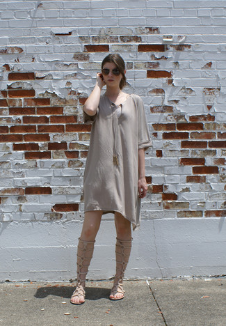 Comment porter une robe trapèze grise: Choisis une robe trapèze grise pour créer un style chic et glamour. Décoince cette tenue avec une paire de sandales spartiates hautes en cuir beiges.