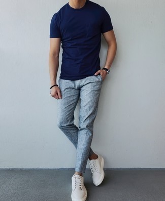 Tenue: T-shirt à col rond bleu marine, Pantalon chino gris, Baskets basses en toile blanches, Montre en cuir noire
