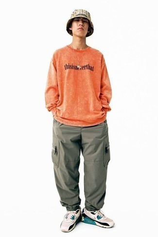 Comment s'habiller à 20 ans: Opte pour un t-shirt à manche longue imprimé orange avec un pantalon cargo olive pour une tenue idéale le week-end. D'une humeur créatrice? Assortis ta tenue avec une paire de chaussures de sport beiges.