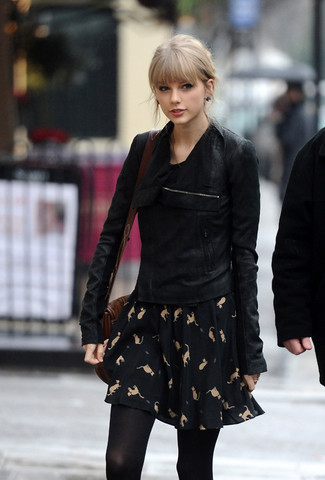 Tenue de Taylor Swift: Veste motard en daim noire, Robe patineuse imprimée noire, Sac bandoulière en cuir marron foncé, Collants noirs